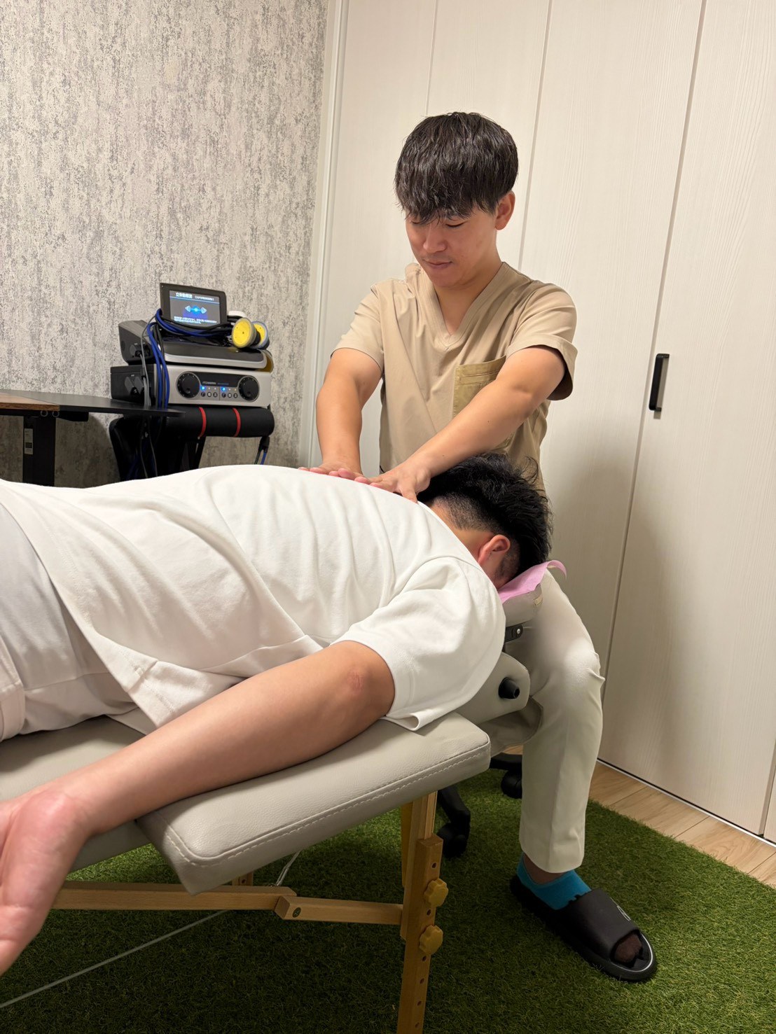 国家資格を持つスタッフが、訪問先で施術ベッドを用いて背中を整える様子
